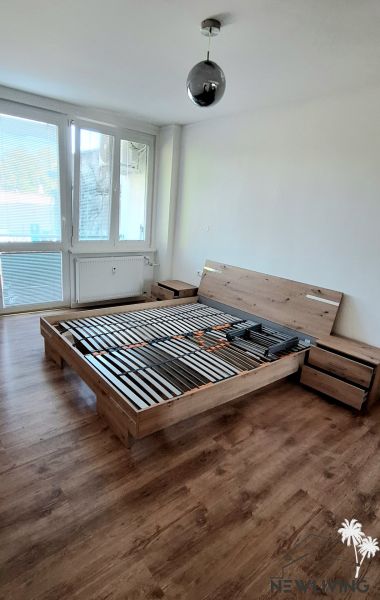 Bedroom in a 2-room apartment with a bed and a floor with a wooden decor.