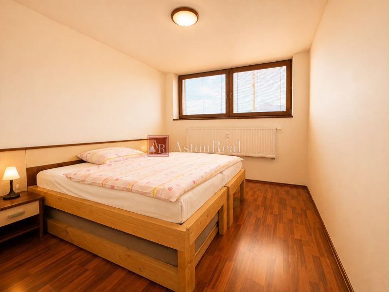 A bedroom with a bed and a wooden decor floor in a 3-room apartment.