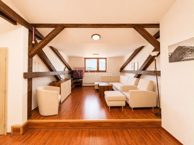 Attic living room with wooden beams and flooring with a wooden decor in a 3-room apartment.
