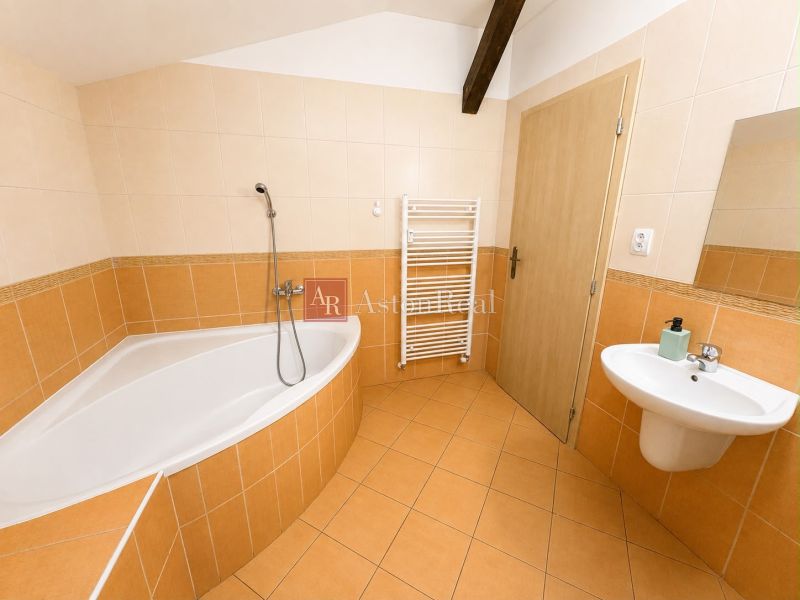 Bathroom in a 3-room apartment with a corner bathtub, sink, and ladder radiator.