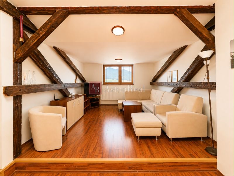 A stylish living room with a wood-patterned floor in a three-room apartment with roof beams.