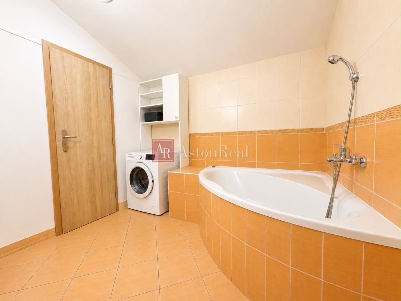 A bathroom in a 3-room apartment with a bathtub and a washing machine.