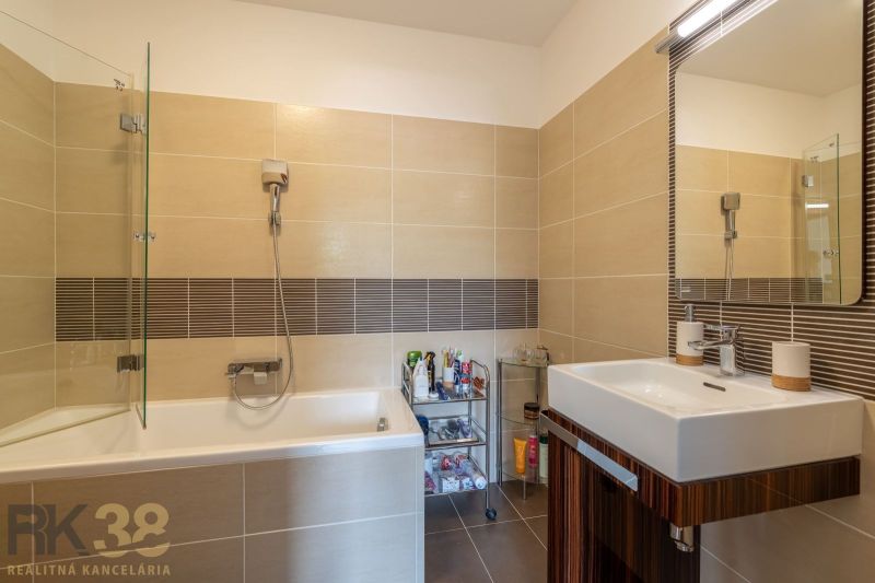 Bathroom in a holiday apartment with a bathtub and a sink on ceramic tiles.