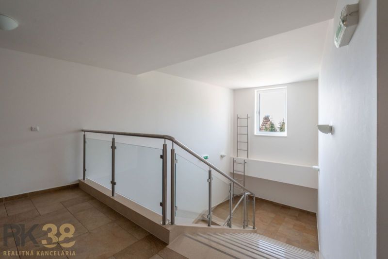 Interior of a staircase in a holiday apartment with wood-patterned flooring and a large window.