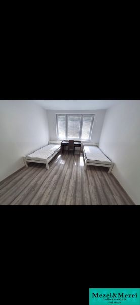 Two beds with mattresses in the bedroom of a 3-room apartment with a wooden decor floor.