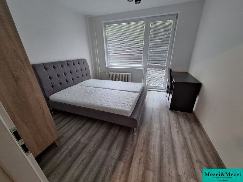 A bedroom in a 3-room apartment with a bed and a floor with a wooden decor.