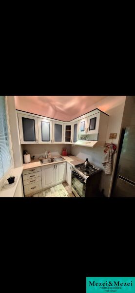 A kitchen in a 3-room apartment with a corner unit and a floor with a wood decor.