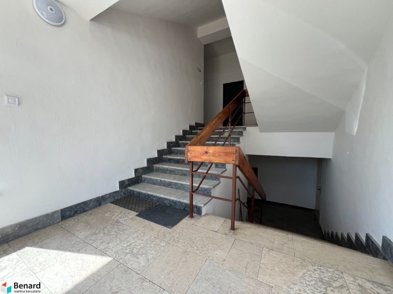 In the office interior, there is a staircase with stone steps and a wooden railing.