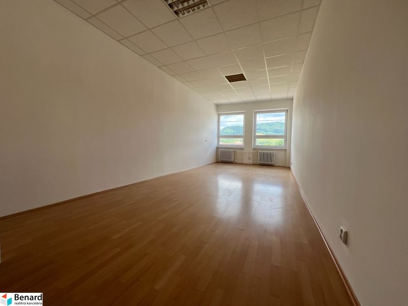 A spacious office with white walls and a wooden decor floor.