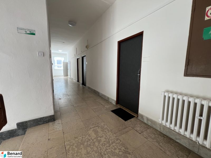 Hallway with tiles, emergency exit, and office doors.