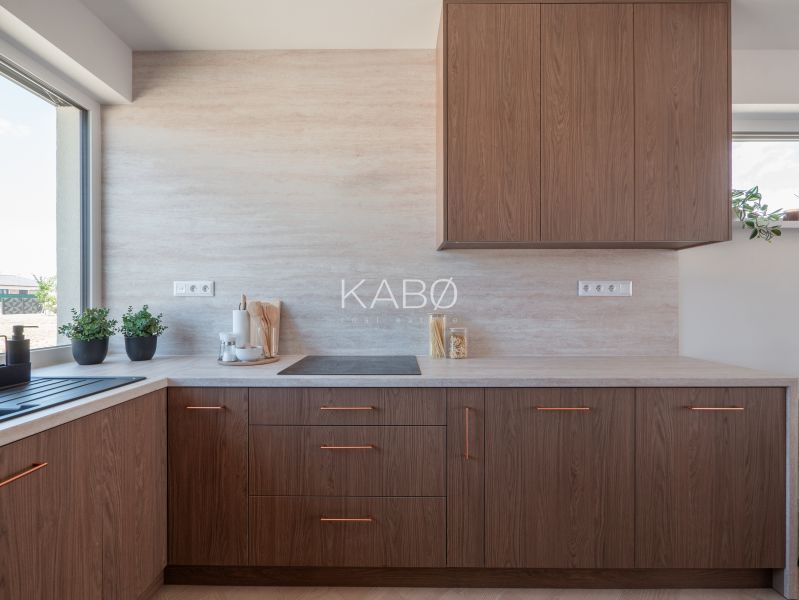 A kitchen in a family house with wooden decor cabinets and a large window.