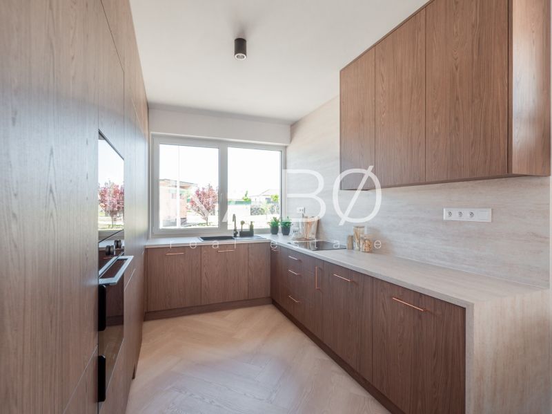 A kitchen in a family house with a window and a wooden decor floor.