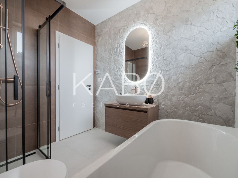 A bathroom in a family house with a stone wall, a sink, and a shower.
