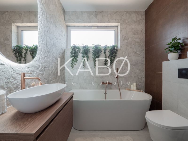 A modern bathroom in a family house with a bathtub, sink, toilet, and flowers.