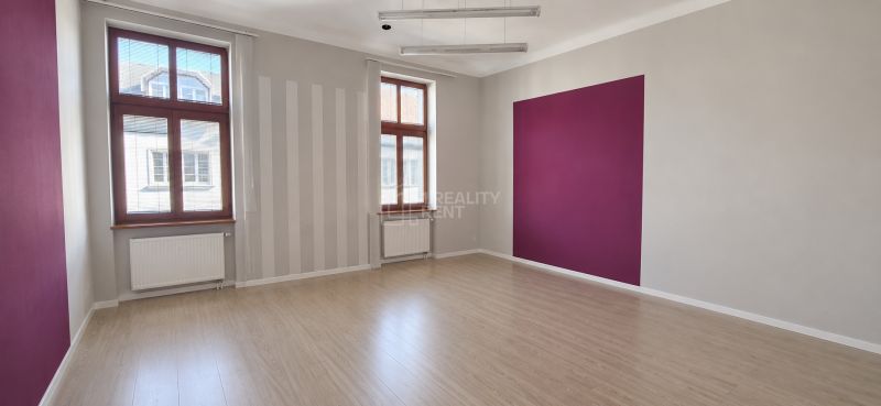 Offices with wood-patterned flooring and a purple wall, large windows, clean lines.
