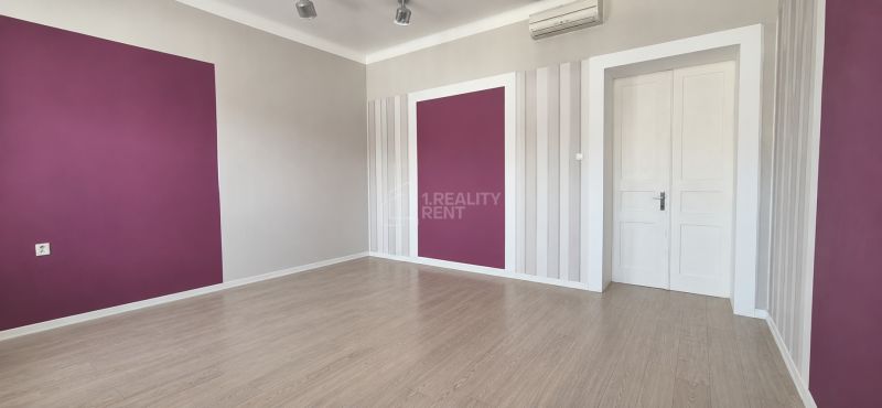 Offices with a purple wall and wood-patterned flooring.
