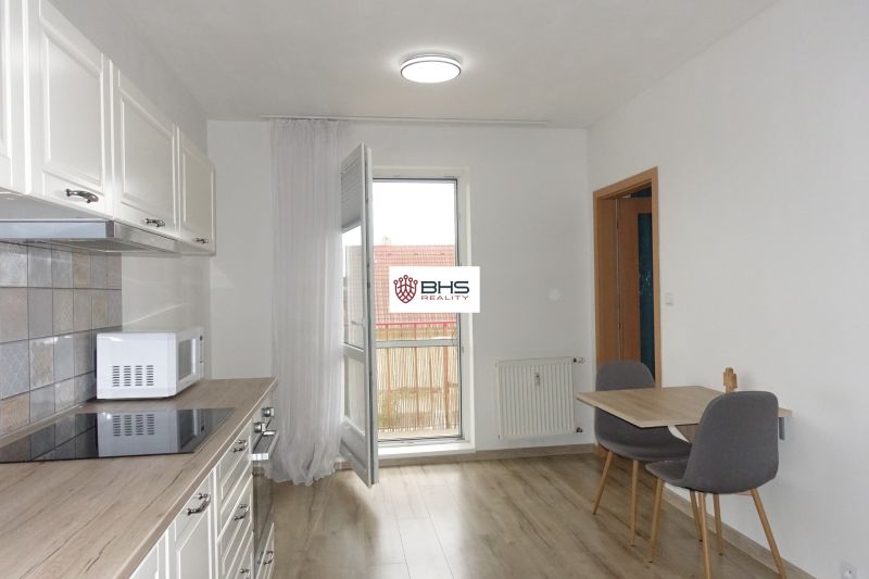 A kitchen in a 2-room apartment with a wooden decor floor and seating for two.