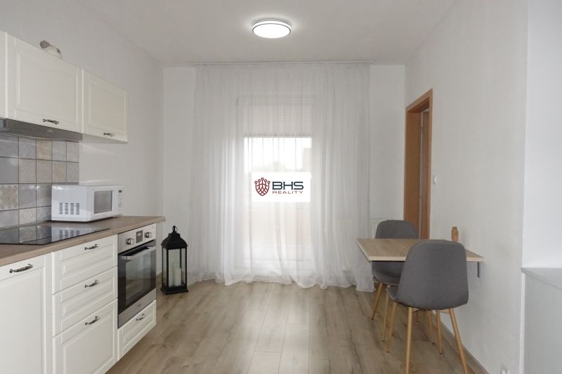 Kitchen corner with equipment, table, and chairs, floor with wooden decor in a 2-room apartment.