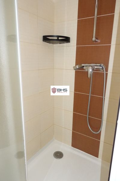 A shower corner with beige-brown tiles in a 2-room apartment.
