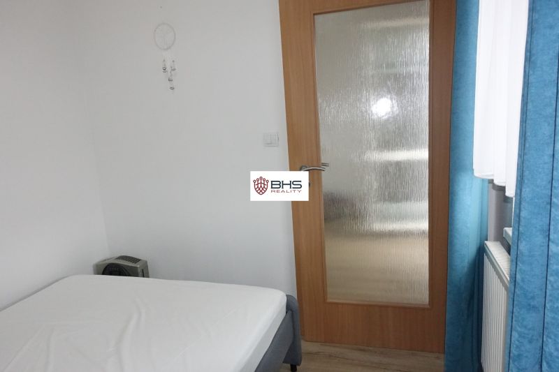 Bedroom in a 2-room apartment with a bed, glass doors, and curtains.