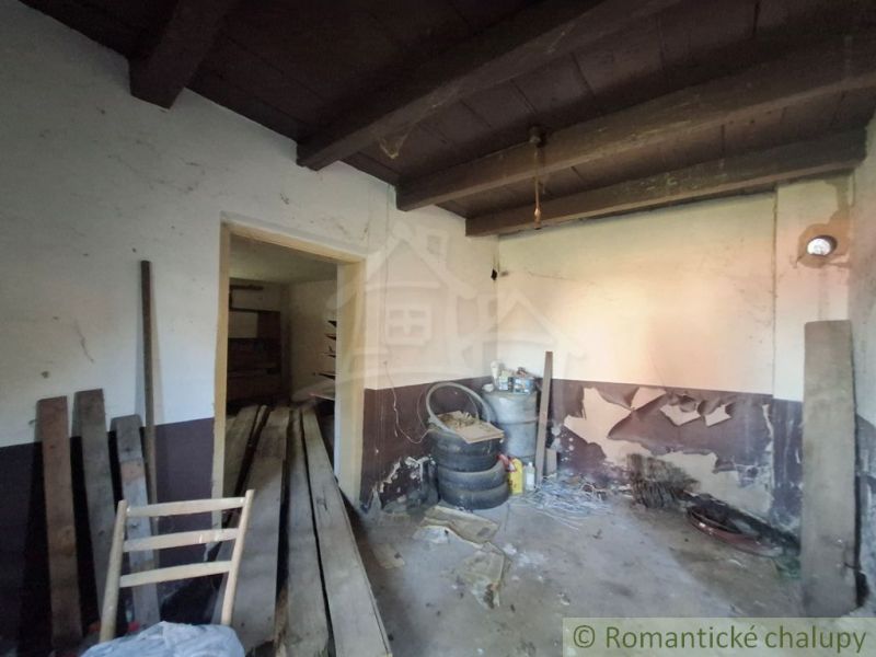 Room with building materials, barrels, and damaged walls in a family house.