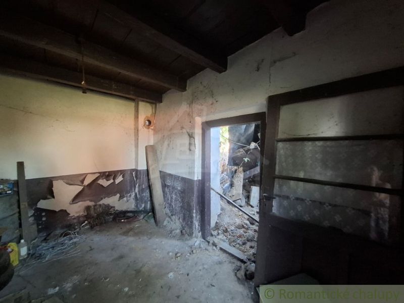 The interior of a family house with peeled walls and open doors leading outside.