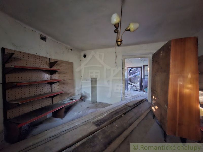 The interior of a family house with shelves and a chandelier appears neglected.