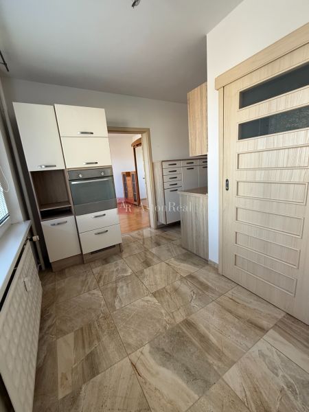 A kitchen in a 3-room apartment with tiles and light furniture.