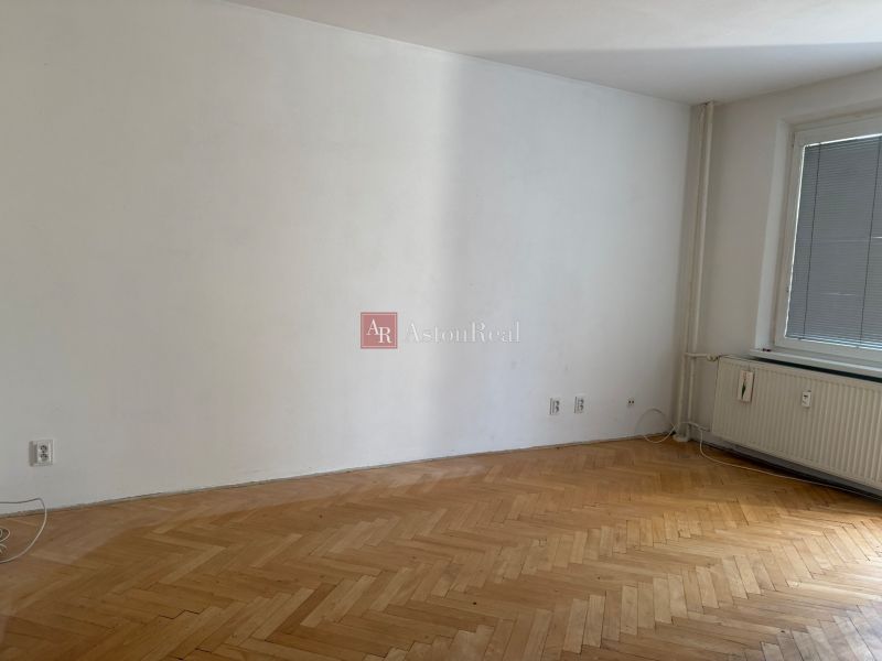 A room in a 3-room apartment with a light wall and a wooden decor floor.