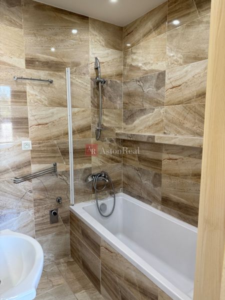 Bathroom with a bathtub and tiles with a natural decor in a 3-room apartment.