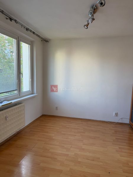 A room with white walls, windows, and a wooden decor floor in a 3-room apartment.