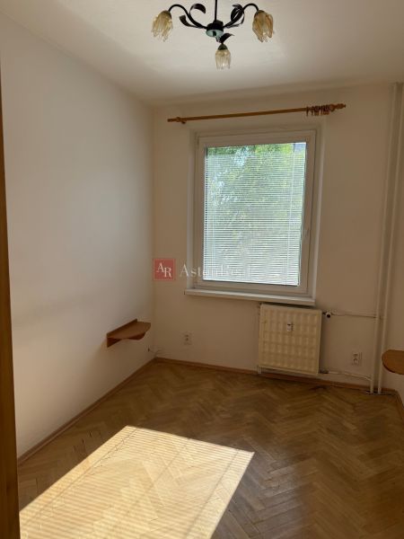 A room in a 3-room apartment with a wooden decor floor and a pendant lamp.