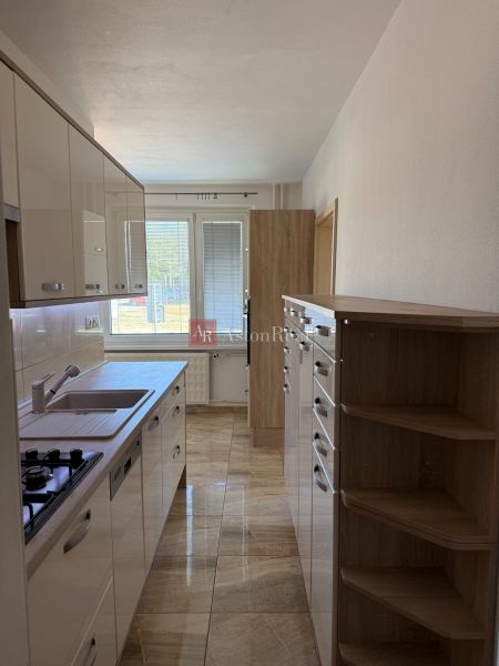 A kitchen in a 3-room apartment with tiles and light kitchen cabinets.