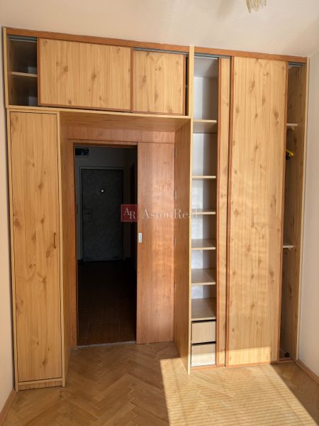 Built-in wardrobe with shelves and doors in a 3-room apartment, floor with wooden decor.