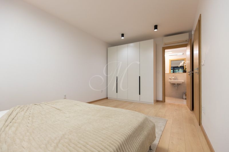 Bedroom with a wardrobe and a bathroom in a 4-room apartment, floor with wood decor.