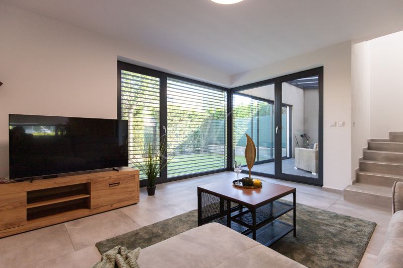 Living room in a 4-room apartment with a wood-patterned floor and large windows.