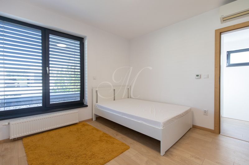 A bedroom in a 4-room apartment with a single bed, a yellow carpet, and a wooden decor floor.