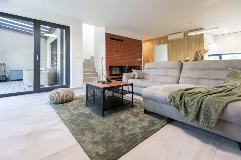 A spacious living room with a sofa, carpet, and transparent doors in a 4-room apartment.