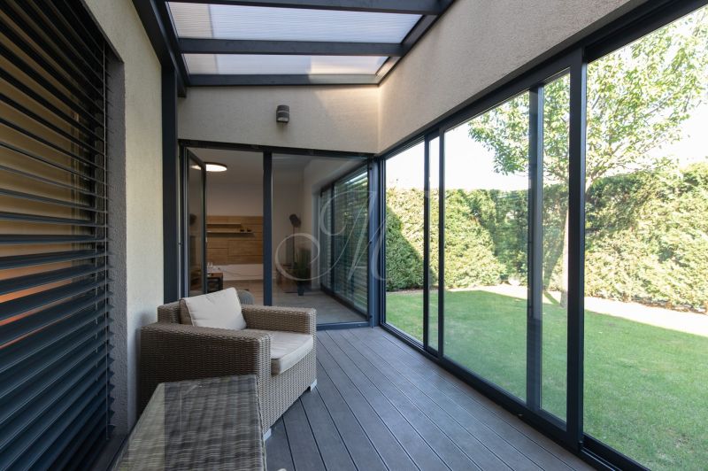 A glazed terrace with seating in a 4-room apartment and a view of the garden.