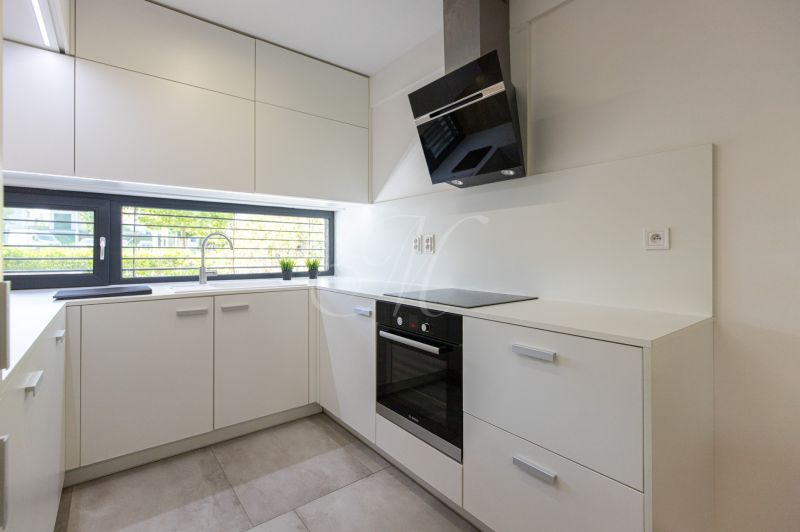 A kitchen in a 4-room apartment with white cabinets and a large window.