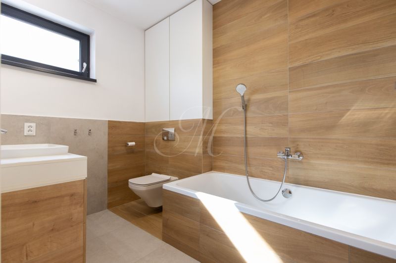 A bathroom in a 4-room apartment with a wood-patterned floor and a bathtub.