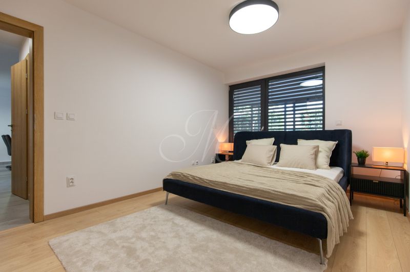 A bedroom with wood-patterned flooring, a large bed, and nightstands.