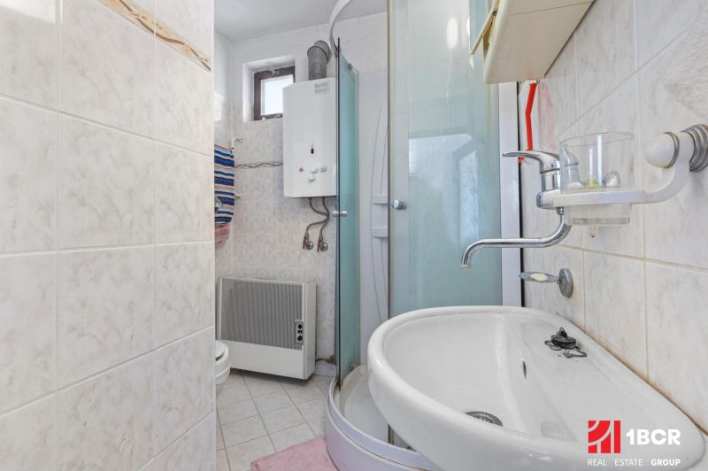 A bathroom in a family house with tiles and a shower corner.