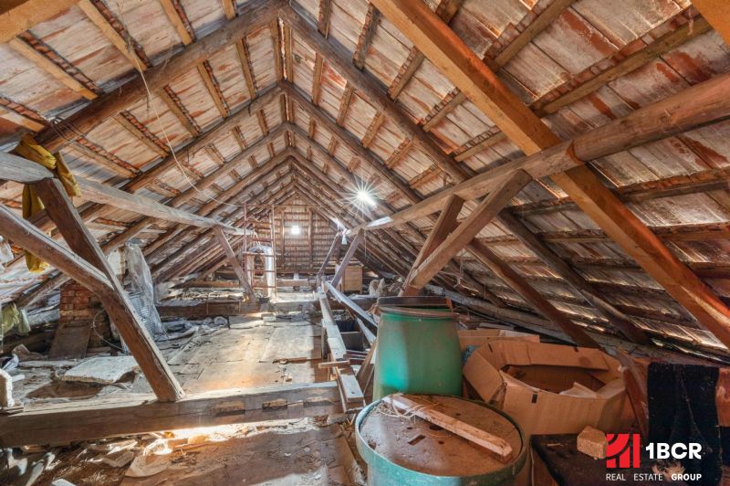The attic in a family house with wooden beams and stored items.