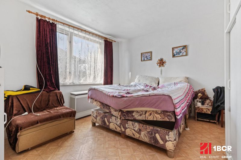 A bedroom in a family house with a sofa and a bed on the floor with wooden decor.