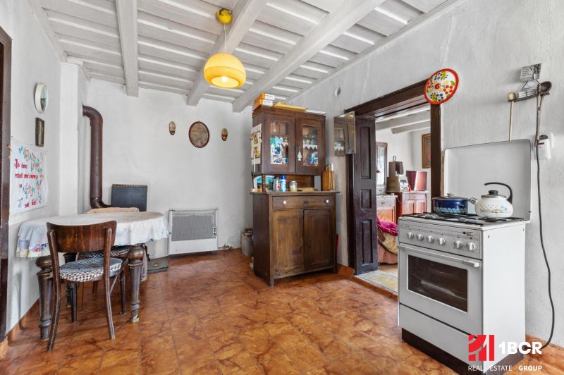 A kitchen in a family house with a stove, a cooker, and wooden furniture.
