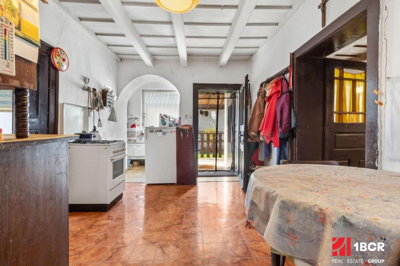 A kitchen in a family house with an arched doorway, a dining table, and a floor with a wooden design.