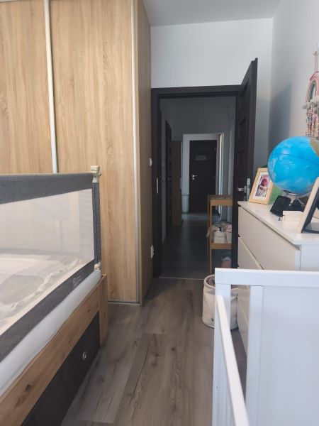 Children's room in a 3-room apartment with a wooden decor floor, wardrobe, and chest of drawers with decorations.