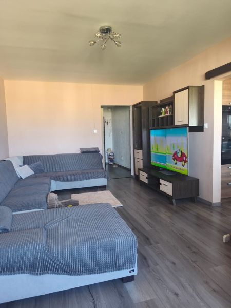 Living room with wood-patterned flooring and a large corner sofa in a 3-room apartment.