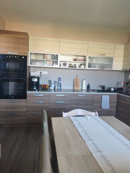 A kitchen in a 3-room apartment with a wooden decor floor, a dining table, and a kitchen unit.